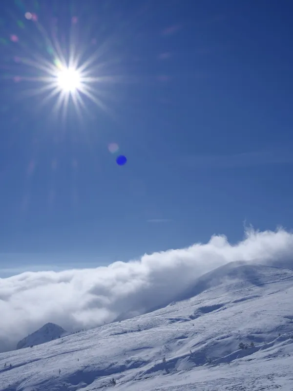 Kar sırtı boyunca yuvarlanan bulutlar ve güneş yıldızı.