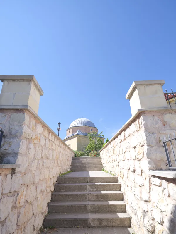 Külliyeye çıkan taş merdiven; arkada caminin kubbesi.