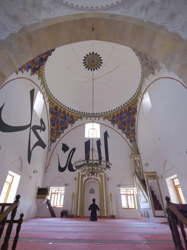 Cami içi: kubbe göbeği, hat yazıları ve avize.